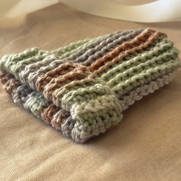 Side view of ribbed baby beanie folded neatly to showcase thick texture, color variation, and clean edge work in a soft natural light setting.