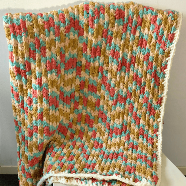 Chunky Crochet Blanket in multicolor hanging on a chair