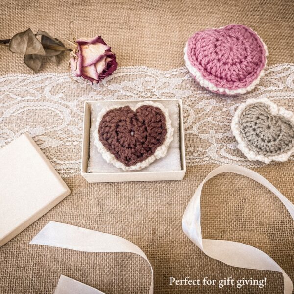 Crochet puffed heart keepsake displayed in a gift box with lace ribbon, dried rose, and two additional hearts on burlap background – handmade Valentine’s or gift idea.
