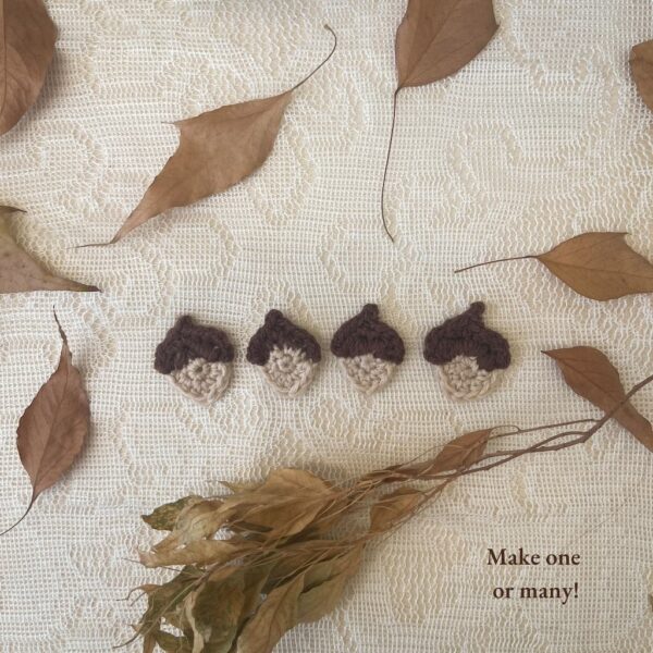 Line of four crochet acorn appliqués displayed on lace background with leaves — make one or many.